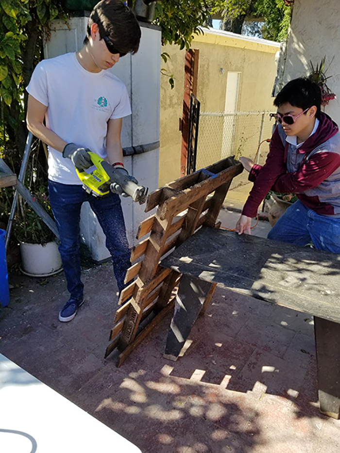 Team members cutting into a wood palette