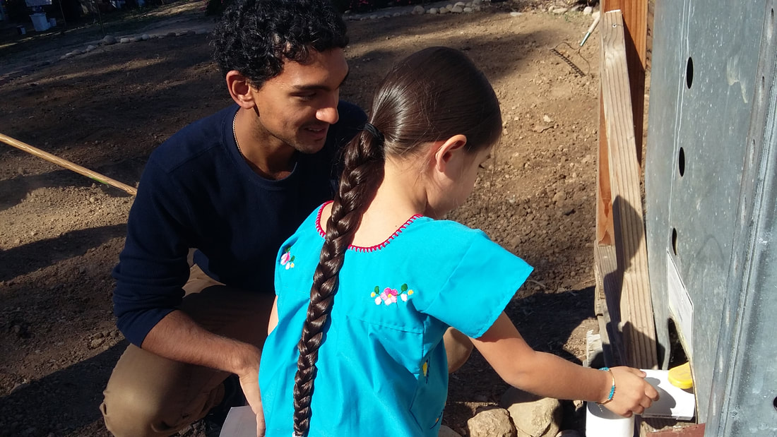 Team member assisting participant in using irrigation prototype